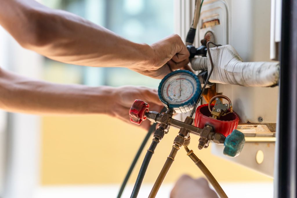 HVAC technician checking system pressures with manifold gauges during a repair visit